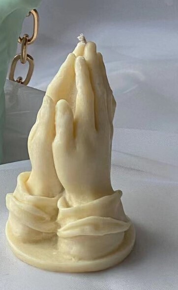 Hands in prayer candle