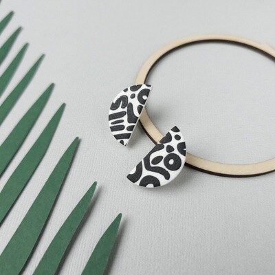 A pair of half-moon polymer clay earrings featuring a black and white abstract design.