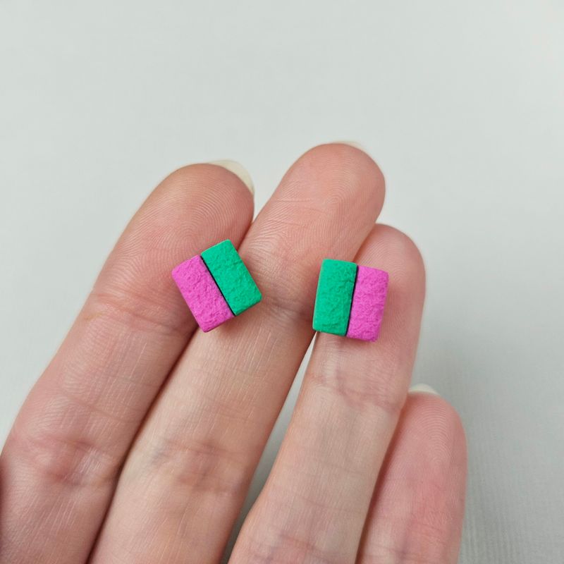 A pair of square stud earrings with a pink and green colour scheme. The earrings are made of textured polymer clay.