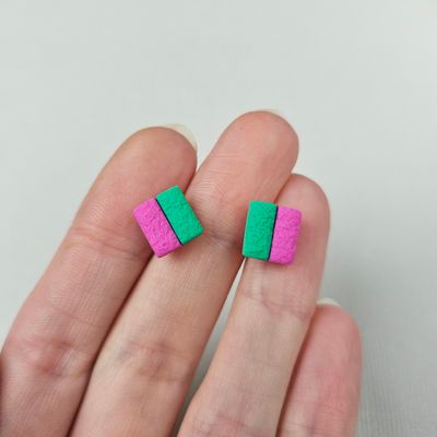 A pair of square stud earrings with a pink and green colour scheme. The earrings are made of textured polymer clay.