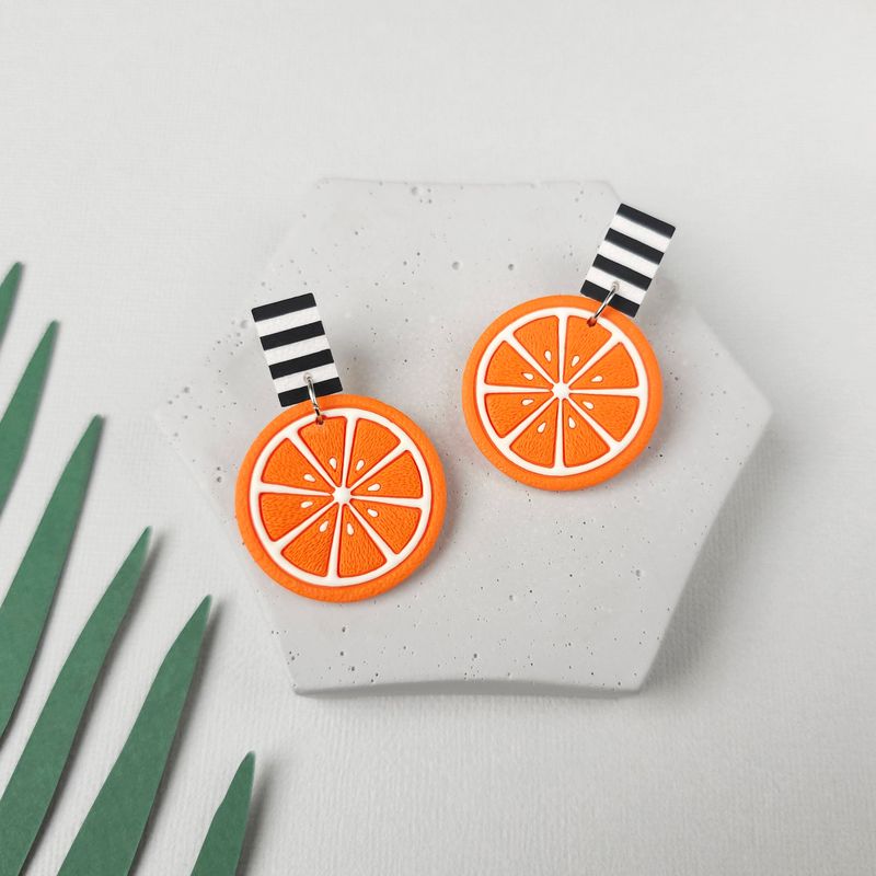 A pair of orange fruit earrings with a black and white striped upper bead. Each earring features an orange slice design.