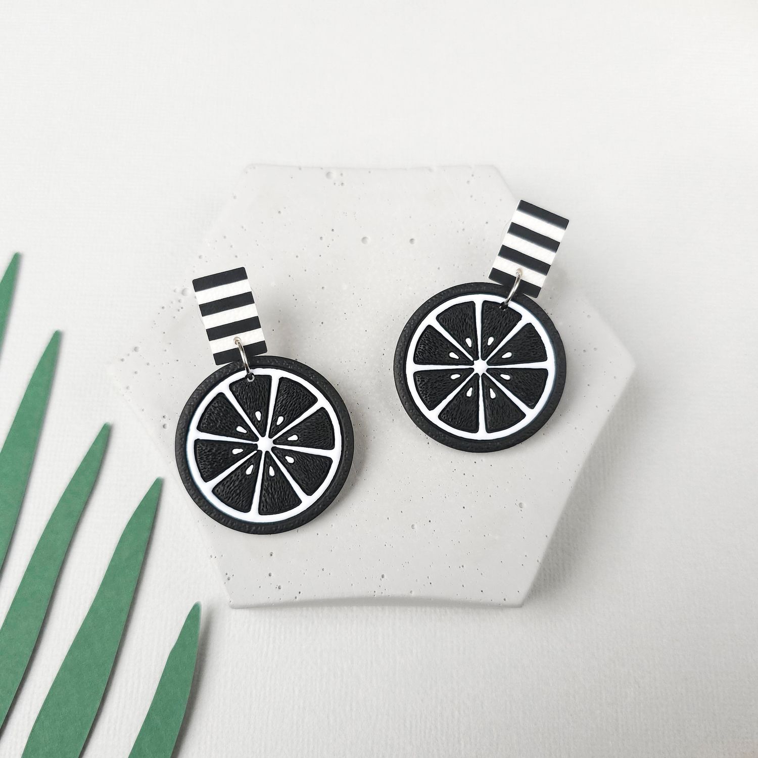 A pair of black and white striped earrings with a black and white lemon slice design for a goth vibe.