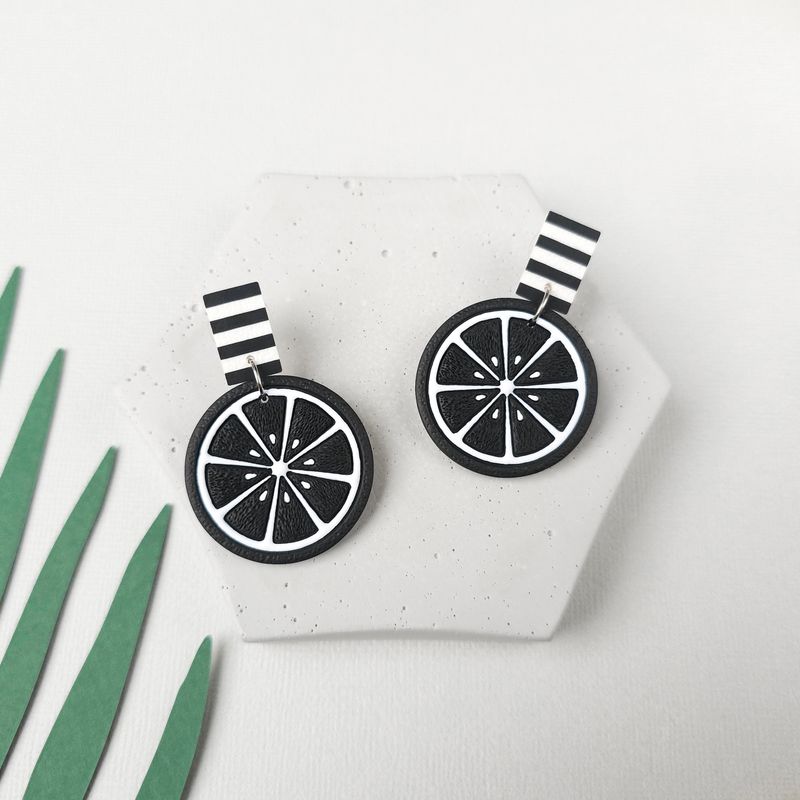 A pair of black and white striped earrings with a black and white lemon slice design for a goth vibe.