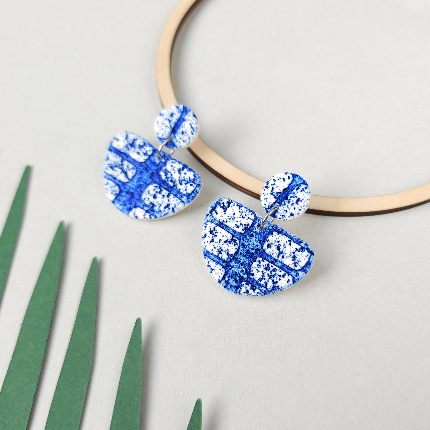 A pair of textured blue and white polymer clay earrings.