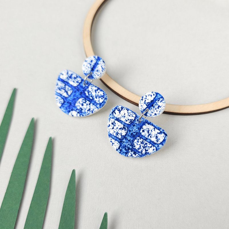 A pair of textured blue and white polymer clay earrings.