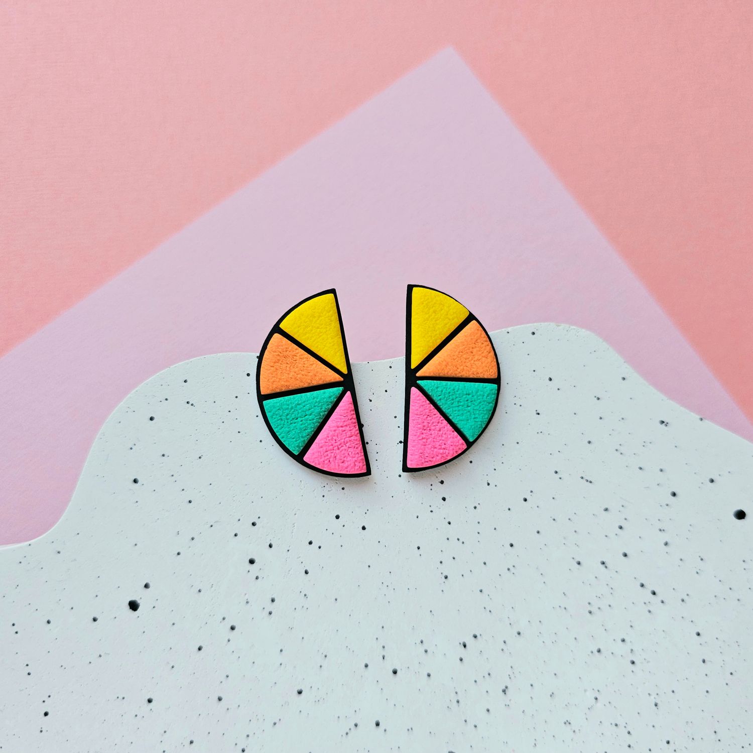 A pair of colourful half-circle earrings with yellow, orange, green and pink sections on a black base.