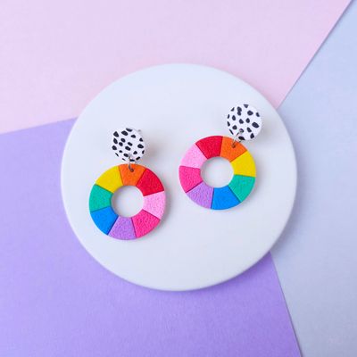A pair of dangle earrings featuring a rainbow colour wheel design and a black and white polka dot upper bead.