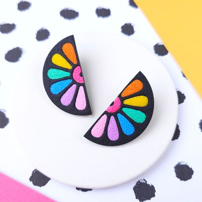 Two black, semi-circular earrings with a colourful petal design in orange, yellow, green, blue, purple and pink.