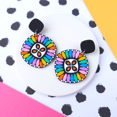 A pair of colourful dangle earrings with a black backing.