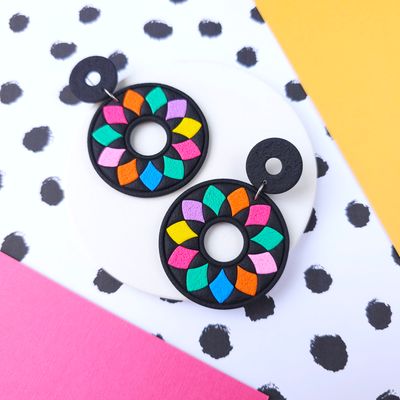 Black, circular earrings with a colourful, geometric design.