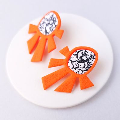A pair of orange statement earrings with a geometric design.
