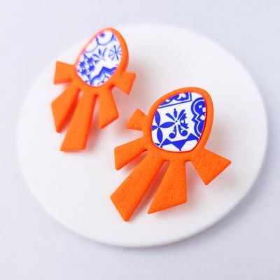 A pair of orange and blue statement earrings with a geometric design.