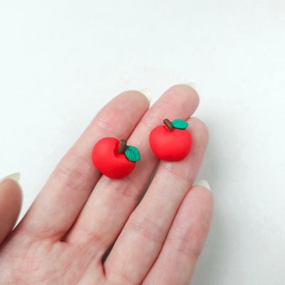 Two small, red apple-shaped stud earrings with green leaves and brown stems.