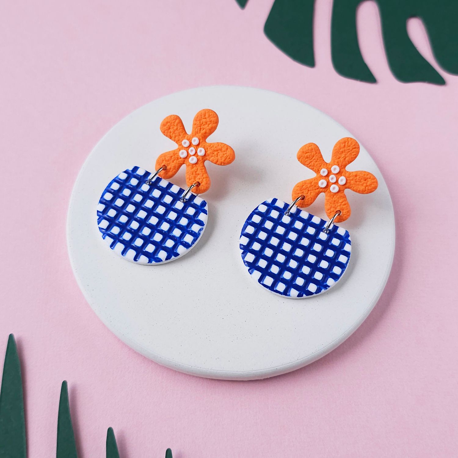 A pair of orange flower earrings, attached to blue and white chequered bottom beads.