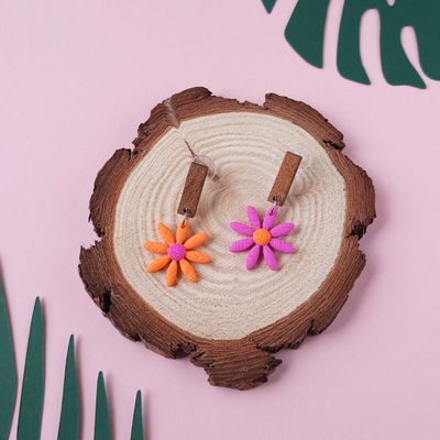 Two daisy earrings, one orange with a purple centre and one purple with an orange centre.