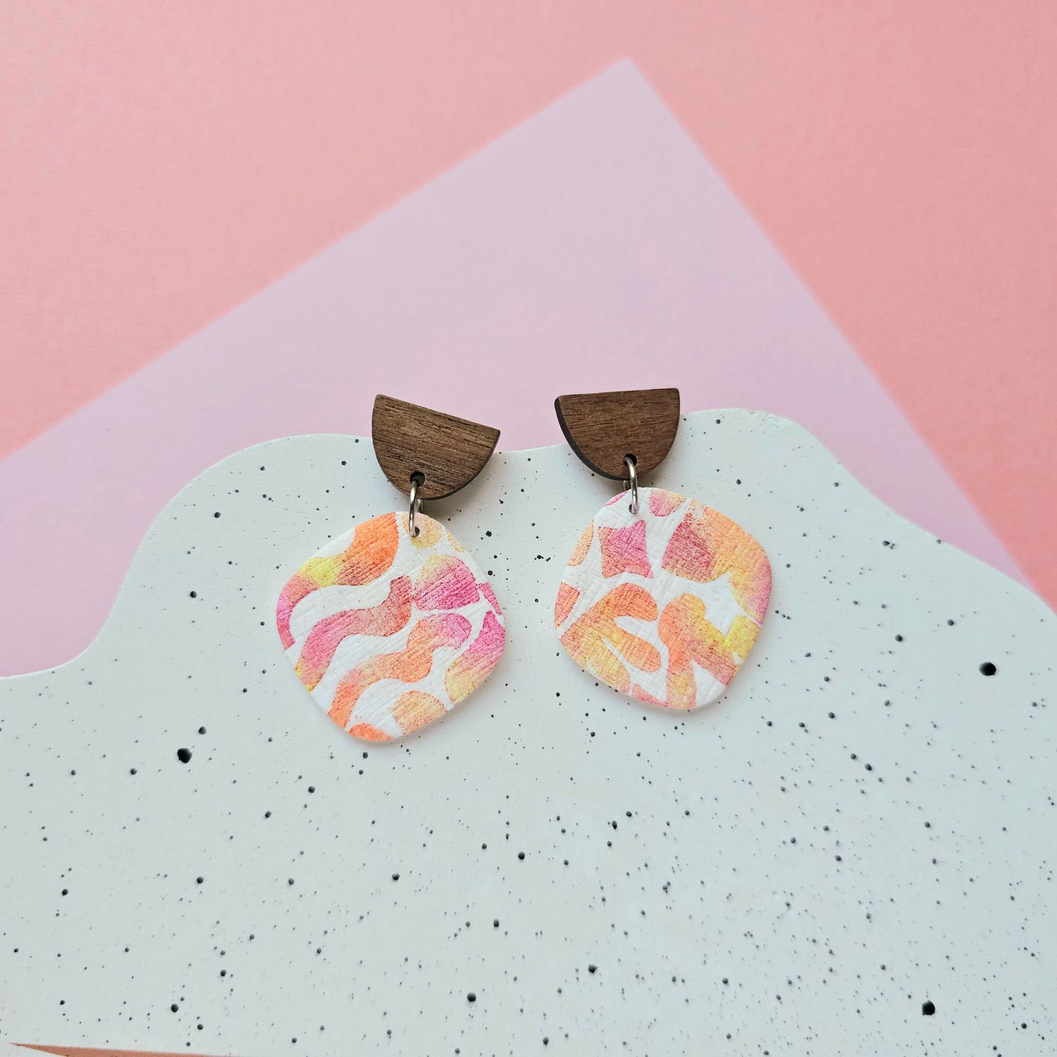 Earrings with a wooden top bead and a colourful, abstract design bottom bead.