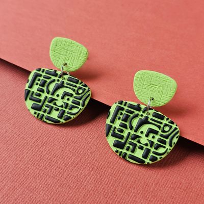 Lime green earrings with a black geometric design.