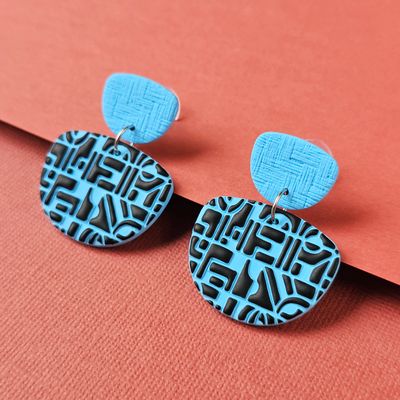 A pair of blue and black geometric polymer clay earrings. 