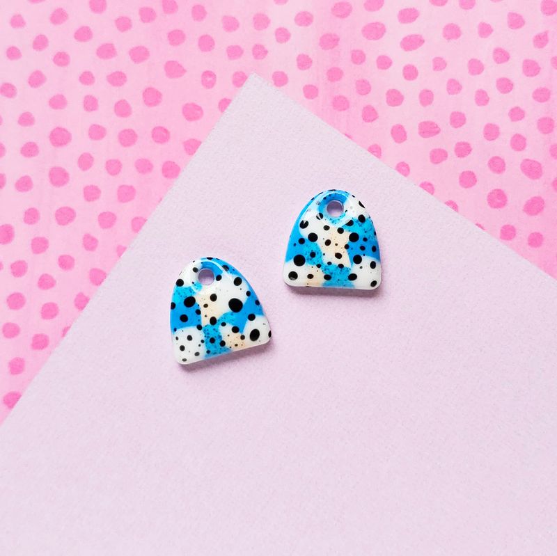 Two abstract charm resin earrings in white, blue, and black, each with a hole at the top.