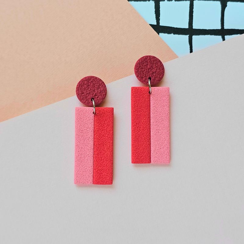 A pair of red, pink, and dark red rectangle polymer clay stud earrings