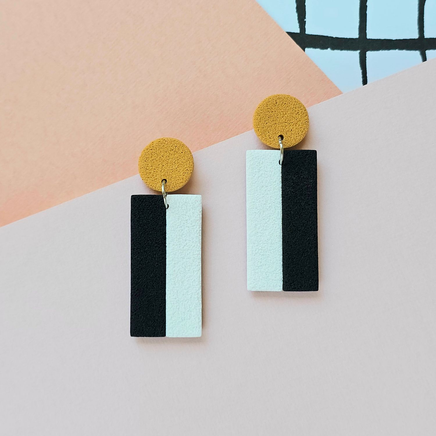 A pair of black, white and ochre rectangle polymer clay earrings.