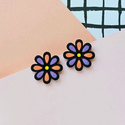 A pair of floral earrings with orange and purple petals enclosed in a black base.