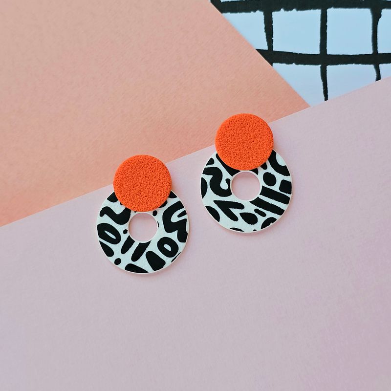 A pair of orange, black and white chunky hoop earrings