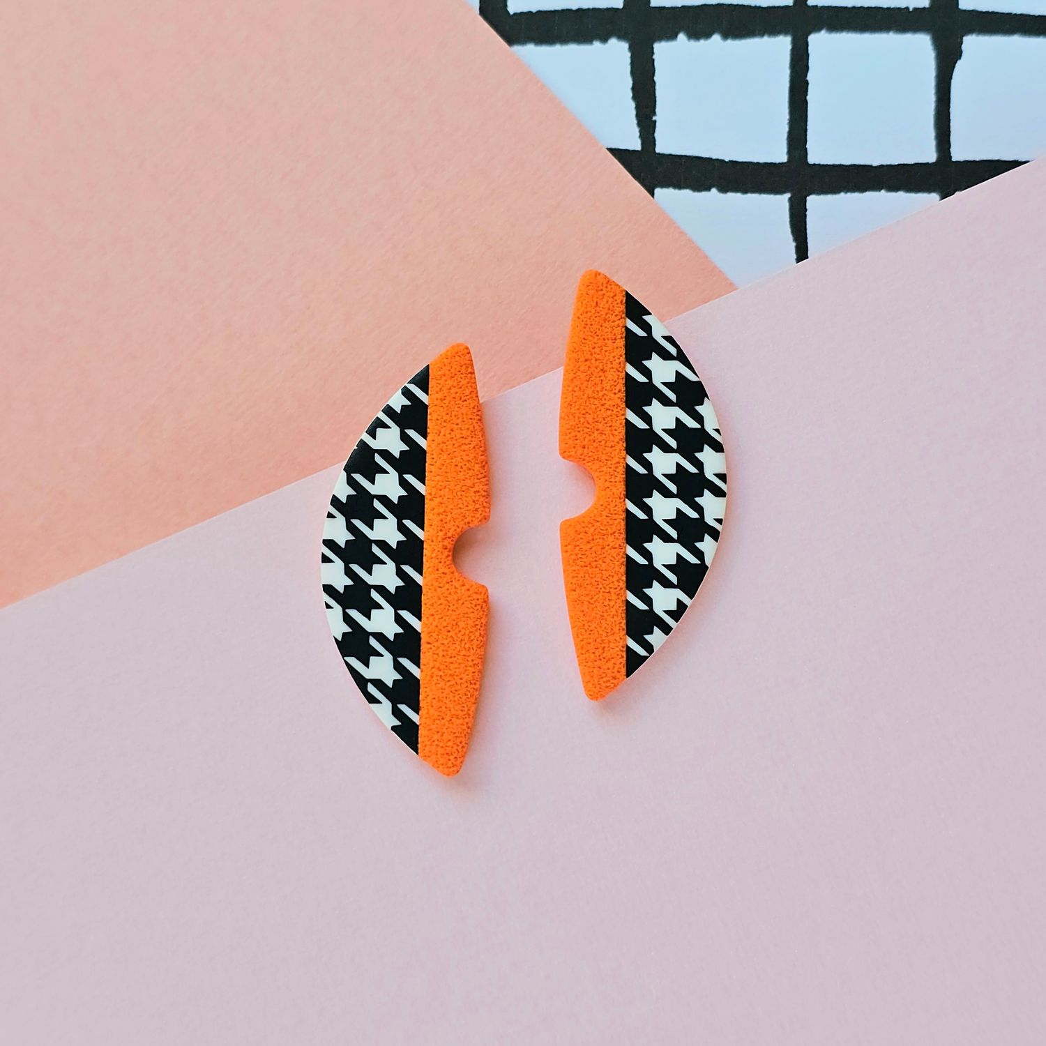 A pair of orange and houndstooth pattern semicircle polymer clay earrings