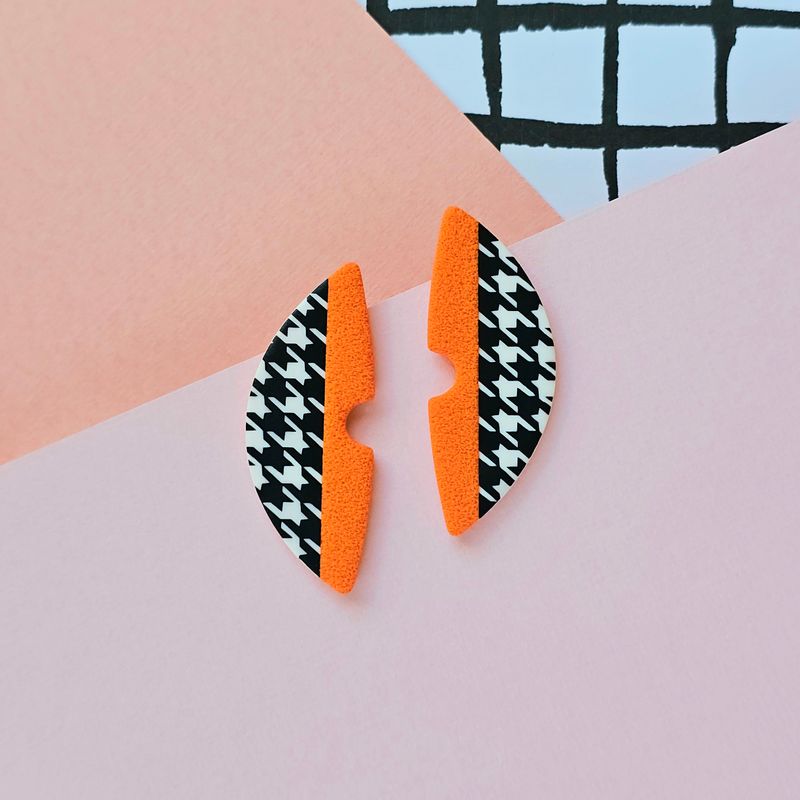 A pair of orange and houndstooth pattern semicircle polymer clay earrings