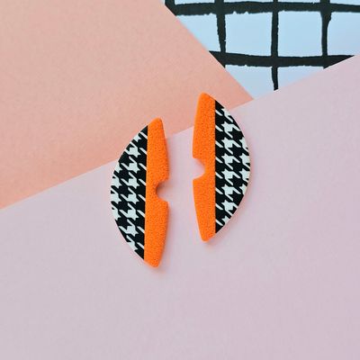 A pair of orange and houndstooth pattern semicircle polymer clay earrings
