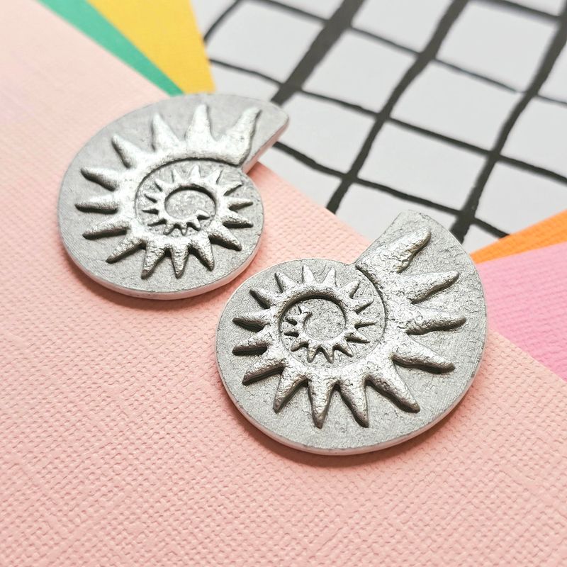 Close up of a pair of silver coloured spiral faux ammonite polymer clay earrings