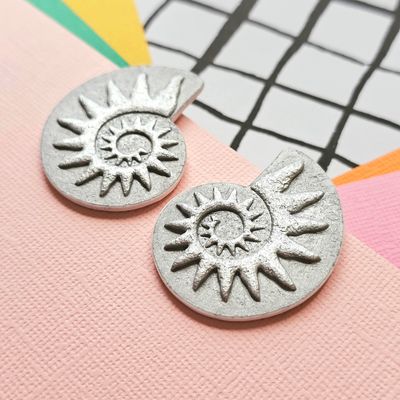 Close up of a pair of silver coloured spiral faux ammonite polymer clay earrings