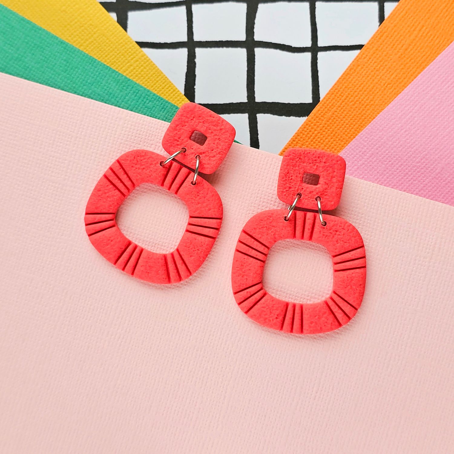 A pair of dark orange statement polymer clay hoop earrings.