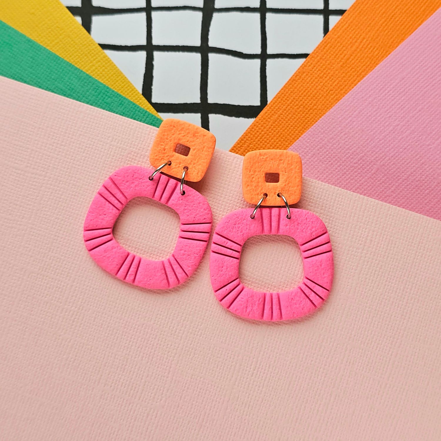 A pair of pink and orange statement hoop polymer clay earrings