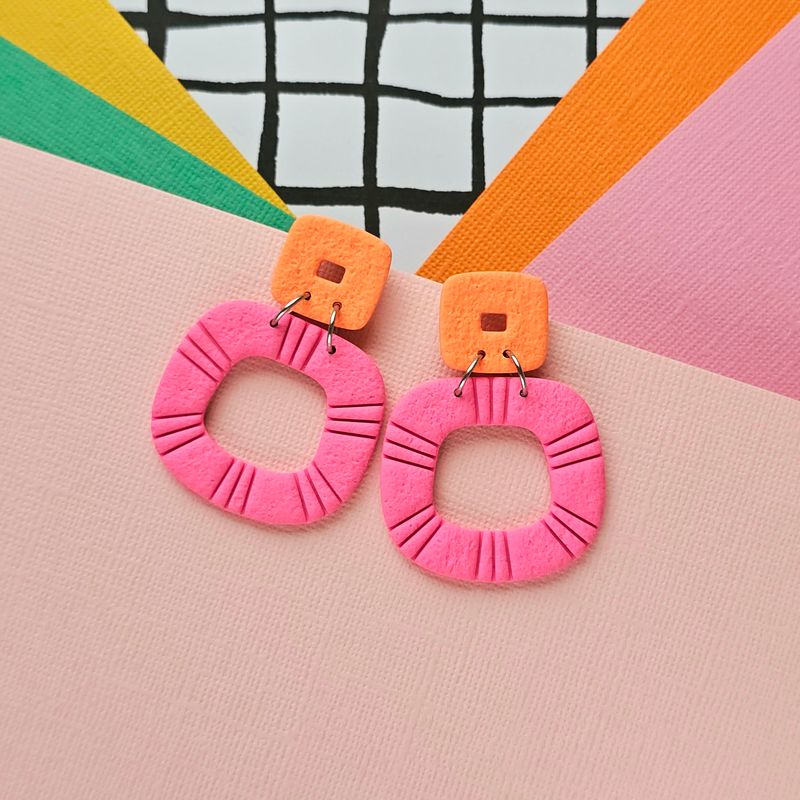 A pair of pink and orange statement hoop polymer clay earrings