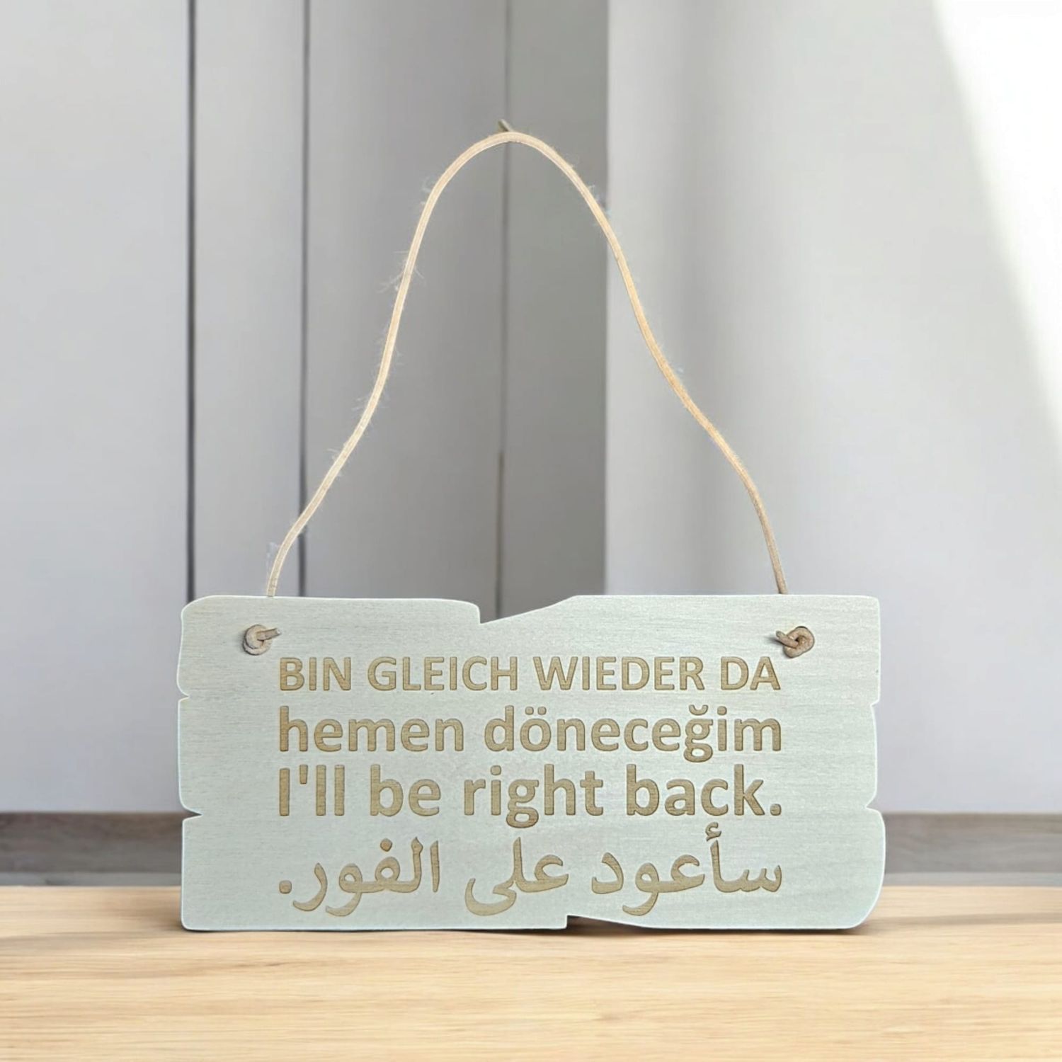 Holzschild BIN GLEICH WIEDER DA In vier Sprachen: Deutsch, Türkisch, Englisch, Arabisch.