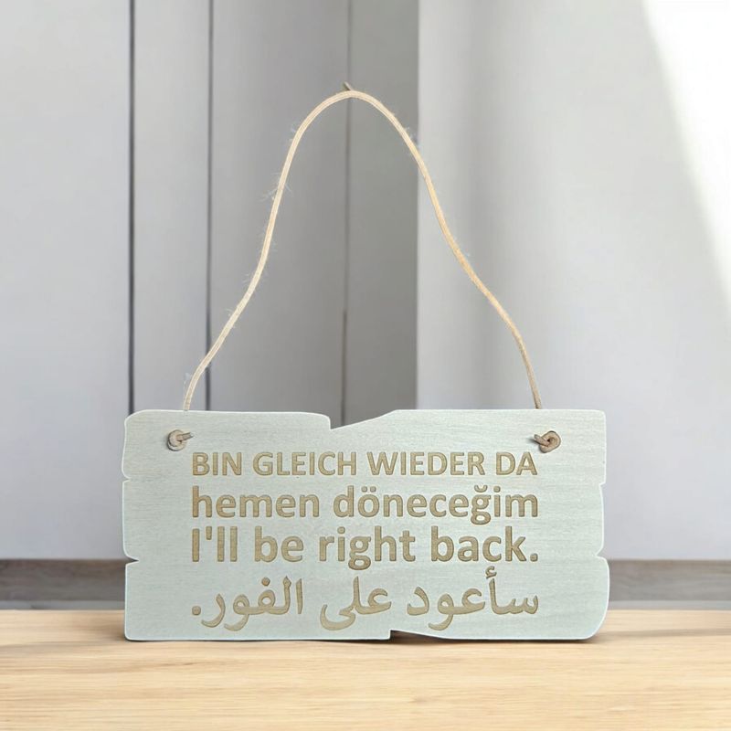 Holzschild BIN GLEICH WIEDER DA In vier Sprachen: Deutsch, Türkisch, Englisch, Arabisch.