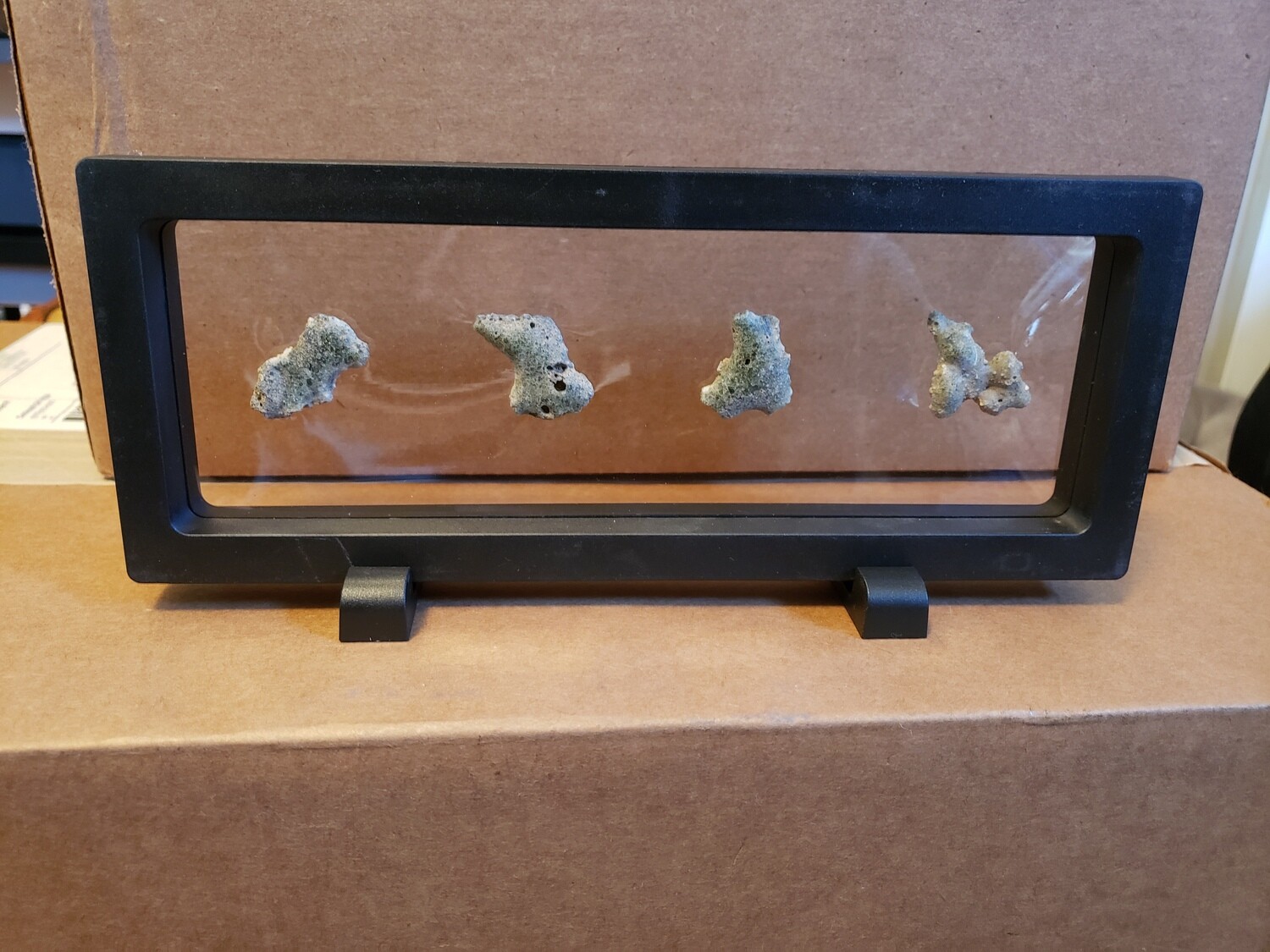 4 pieces of Trinitite in a black 3D frame