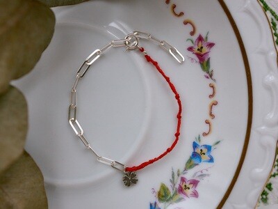 A silver bracelet with a four-leaf clover charm