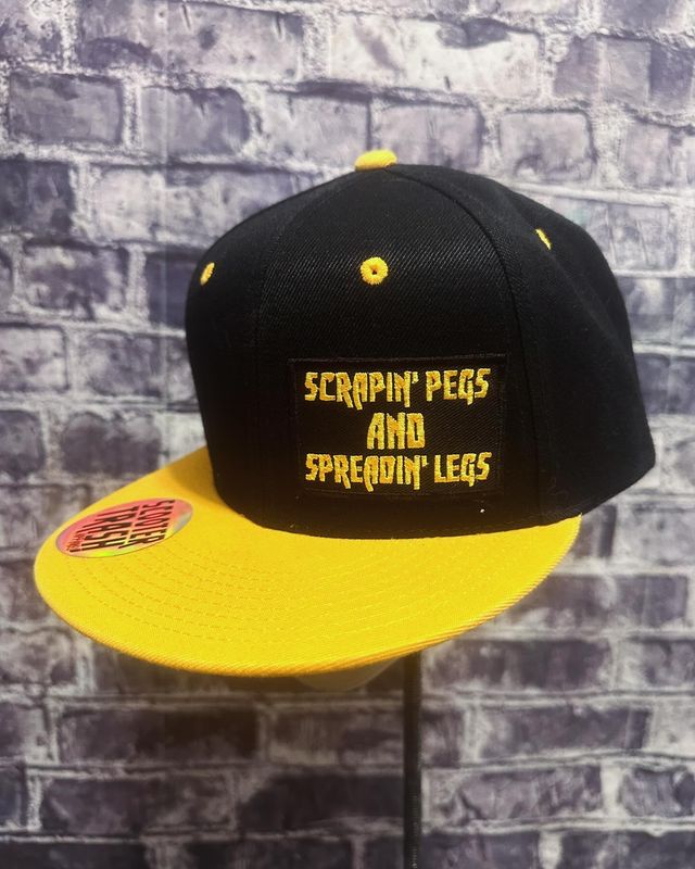 SCRAPIN PEGS AND SPREADIN LEGS- YELLOW/GOLD BILL BLACK BACK - PATCH  - SNAP BACK