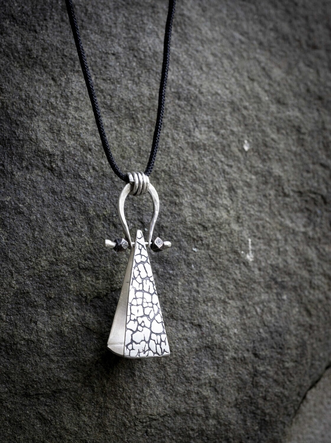 Sterling Silver Triangle Necklace that is 1.75 inches in length.  Similar to a pendulum necklace, it is unisex, and is on a black nylon cord that is 18 inches.