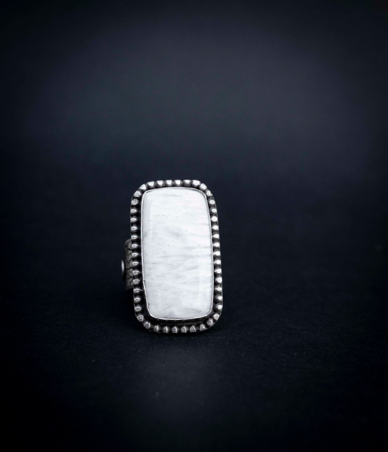 Our Rectangle Scolecite Ring in US Size 8.5.   The gemstone is white and it is set into sterling silver that is textured and oxidized.