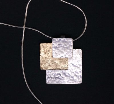 A modernist pendant necklace on a sterling silver snake chain.  This geometric necklace hosts two sterling silver squares that are hand textured, and one gold brass square also hand textured.  1.26 inches in overall height by 1.25 inches in width.  Choice of chain length at check out.  Handmade in the Honey Bee Metals studio.