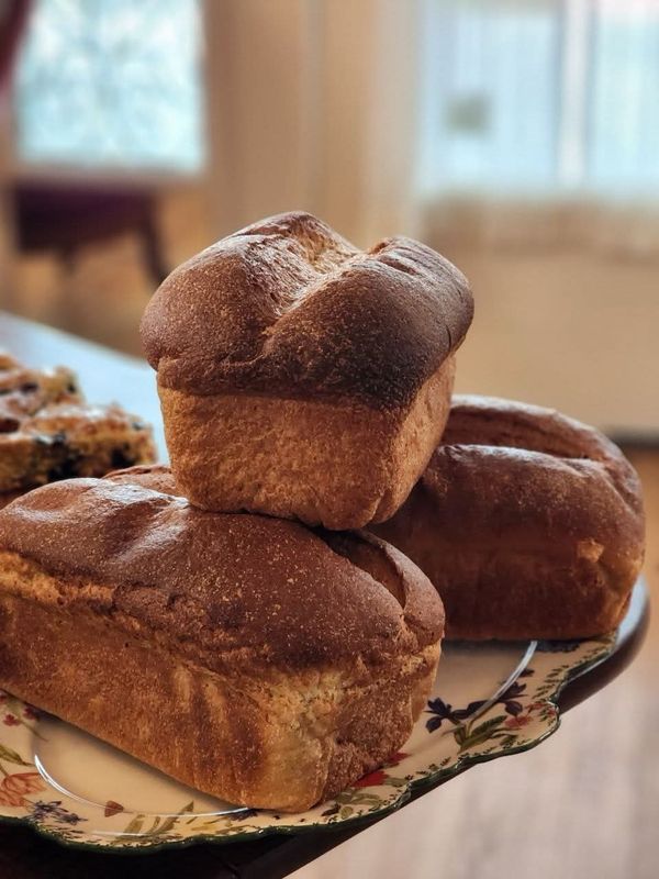Stacked, crusty brown Sourdough Bread loaves, long fermented, on an ornate floral platter—fresh bakery artisan loaves.