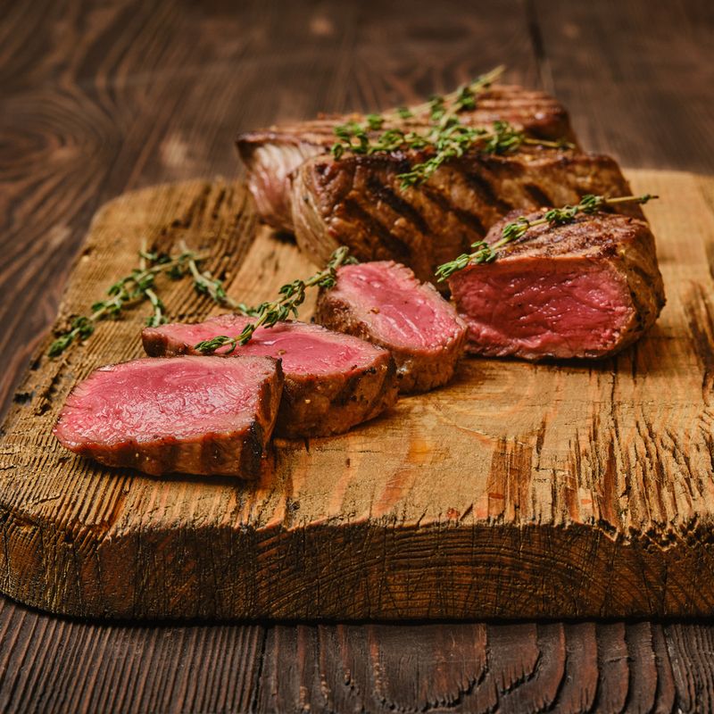 Tip Roast Perfectly cooked Sirloin Tip Roast on a rustic wooden board, sliced to reveal juicy pink medium-rare meat, garnished with fre