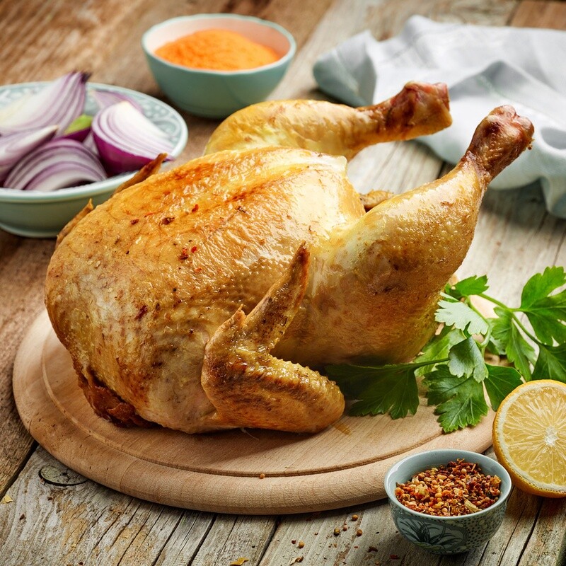 Golden roasted Whole Chicken Freezer Clean Out on a wooden cutting board with herbs, lemon, onions &amp; spices.