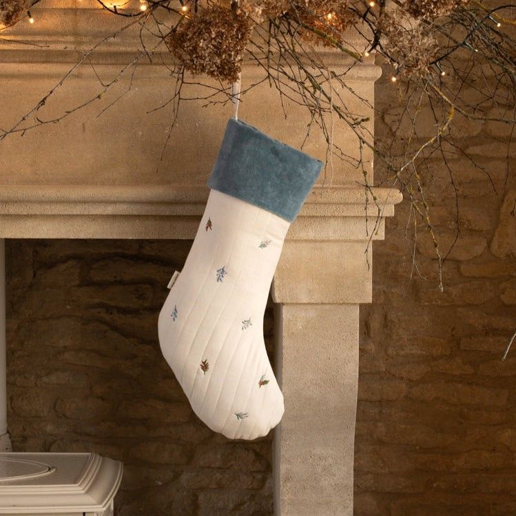 Winter Sprigs Stocking hung on the mantle waiting for Santa. Embroidered with delicate festive foliage and a plush blue trim
