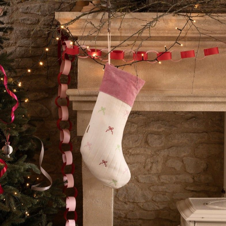 Bow Stocking hung on the mantle waiting for Santa. Embroidered with colourful bows and a plush velvet pink trim