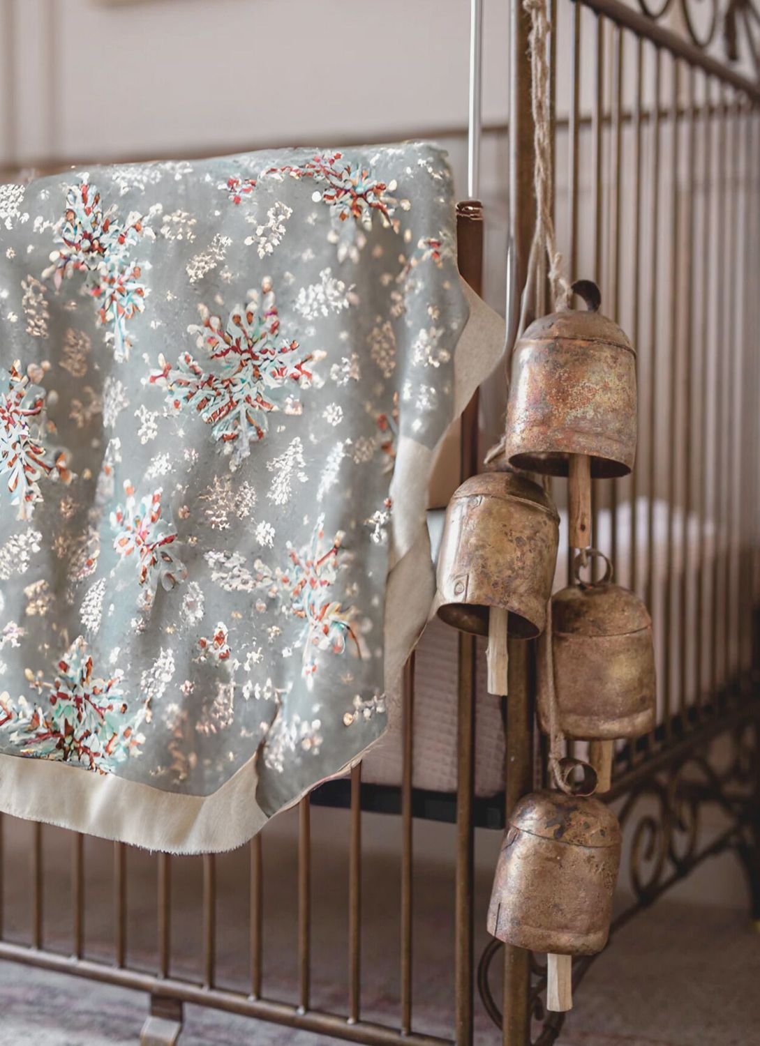 Vintage cot with winter blanket and rustic copper bells—perfect for cosy nursery styling and seasonal cottage décor.