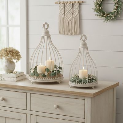 Vintage Ivory Cloches Two vintage style ivory metal caged cloches with ornate bases on feet decorated with candles and green foliage